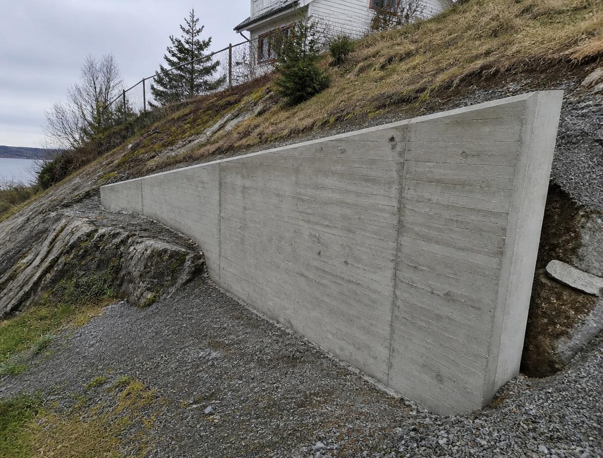Plasstøypt forstøtningsmur som tek opp terrenget ved ein bustadtomt